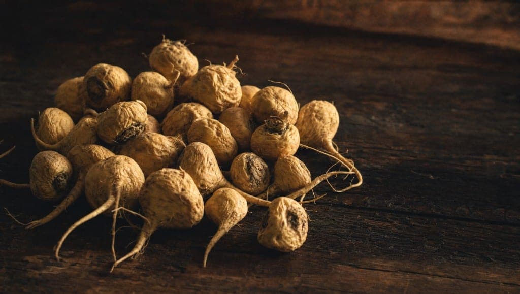 Tas de racines de maca séchées sur une planche de bois sombre